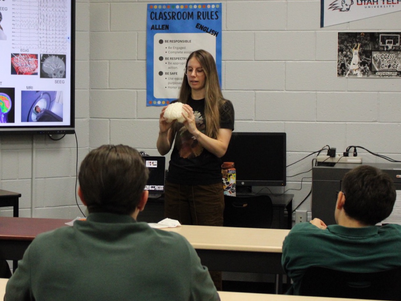 Martina Hollearn holding a model brain while teaching a STEM Community Alliance Program class